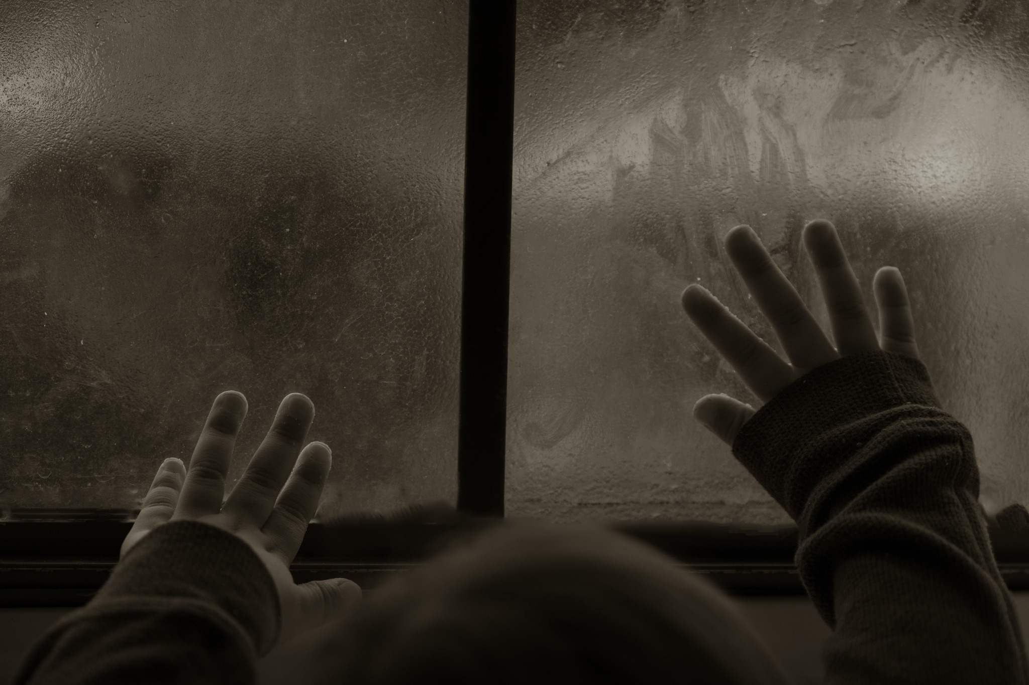 Hands pressed against textured glass in shadow